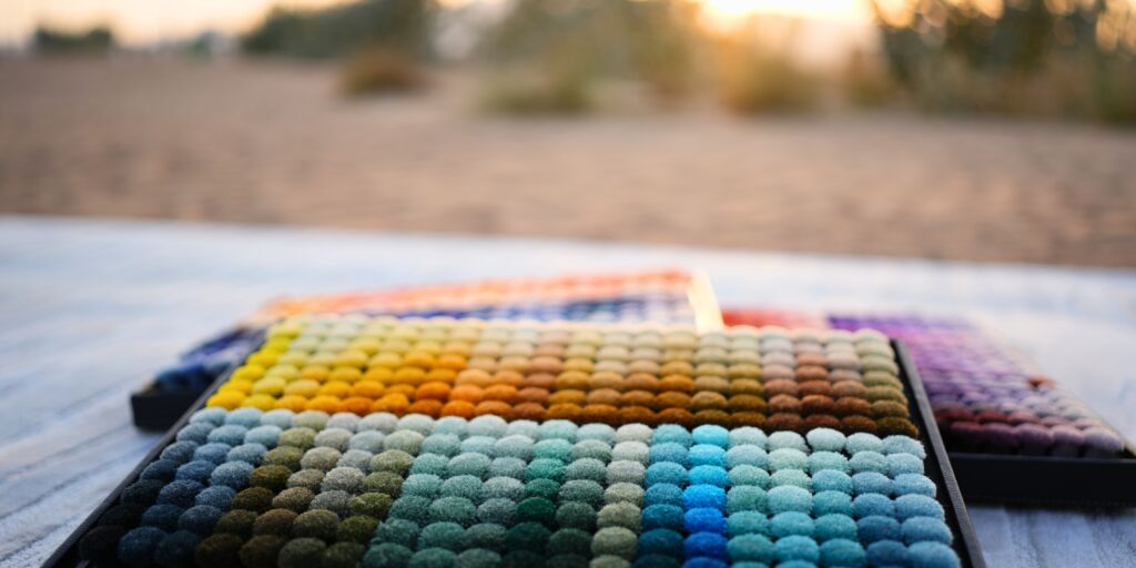 ARS wool poms arranged by color family, showcasing precision-dyed samples used for accurate rug color selection and emotional interior styling.