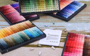 Zodiac rug colors inspired by astrology, featuring wool swatches from Aries red to Pisces lilac arranged in a celestial-themed layout.